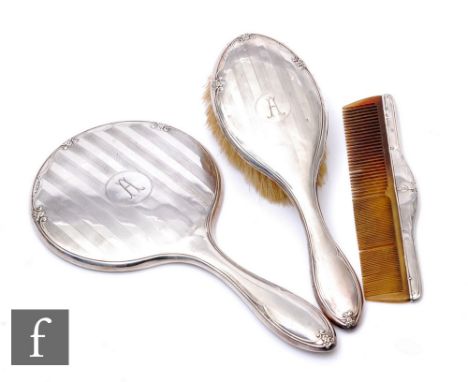 A hallmarked silver three piece brush set, hand mirror, brush and comb, Chester 1927, some damage. (3)