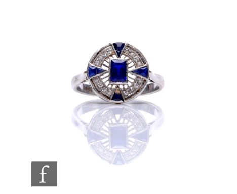 An Art Deco sapphire and diamond ring, circular head set with central emerald cut sapphire within a diamond border and furthe