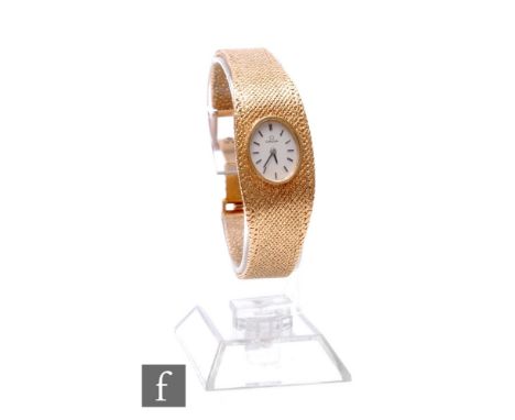 A 1970s lady's 9ct hallmarked Omega, manual wind wrist watch, batons to an oval silver dial and integral mesh link tapering b