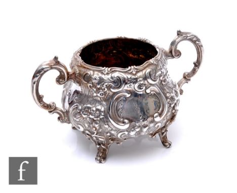 A Victorian hallmarked silver twin handled sugar basin with embossed foliate decoration and raised on four scroll feet, weigh
