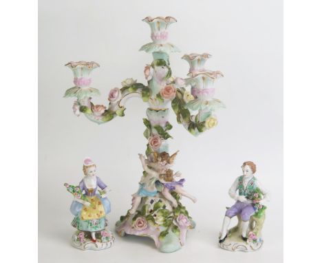 A continental porcelain three- branch candelabra with floral encrusted and cherub decoration 32cm high, together with two sma