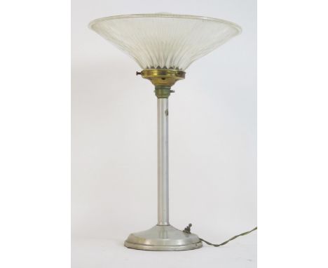 An Art Deco period Holophane aluminium table lamp, with clear glass flared shade, on a weighted circular base. overall height