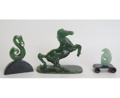 A carved green stone model of a rearing horse, on a rectangular base, 10cm high, 11cm long, together with two jade pendants o