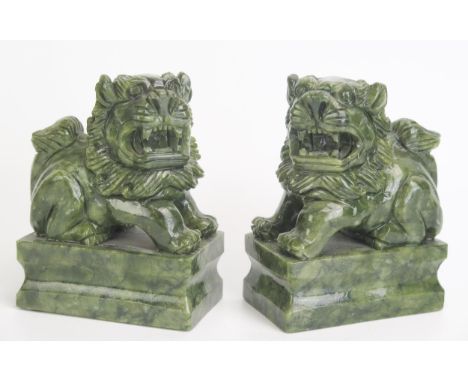 A pair of Chinese jade style figures of temple lions, mounted on rectangular plinth bases12cm high, 9cm long.