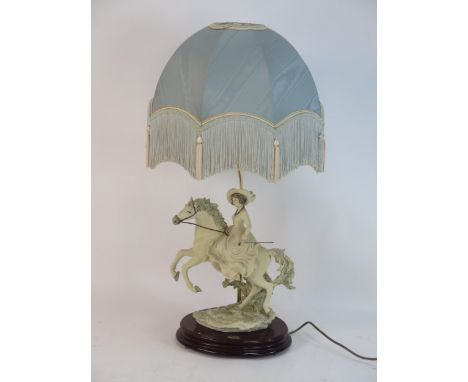 A Florence figural table lamp, modelled as a lady riding side saddle on a horse. raised on a polished wood base, having a sil