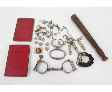 Two pairs of polished steel handcuffs, Metropolitan whistles, Devon Constabulary buttons, badges, books on Self defence The P