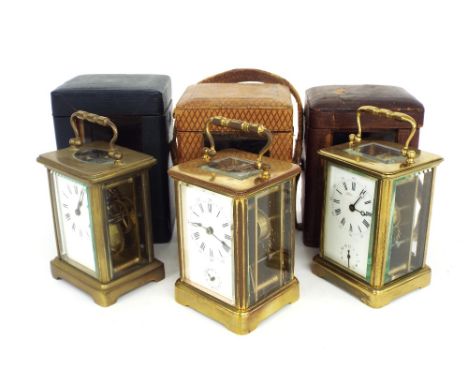 Three various carriage clock timepieces, two with alarms, all approximately 6" high, with three travelling cases