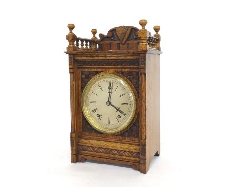 German oak two train mantel clock striking on a gong, the 5" silvered dial within a panelled carved case surmounted by a gall