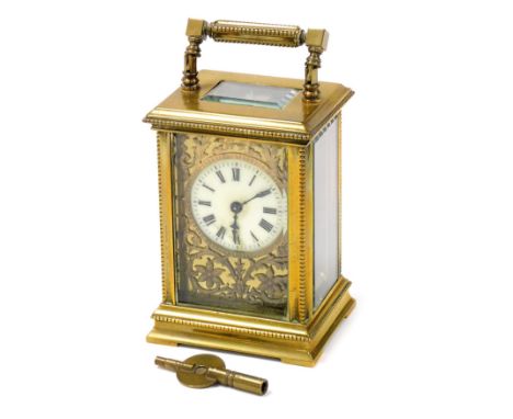 A late 19thC brass cased carriage clock, the circular enamel dial bearing Roman numerals, against a plate worked in relief wi