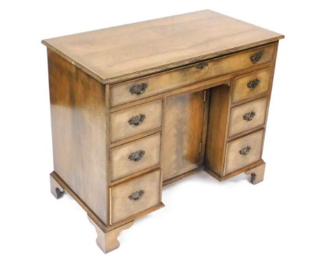 A flame mahogany kneehole desk or dressing table, with a crossbanded quarter veneer top above a frieze drawer and an arrangem