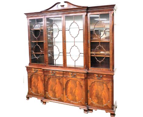 A Charles Barr Georgian style mahogany breakfront bookcase, the swan neck pediment with dentil moulding, above four astragal 