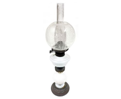 An early 20thC oil lamp, with a clear and etched shade, and milk glass central reservoir, with Greek key decoration, on a gla