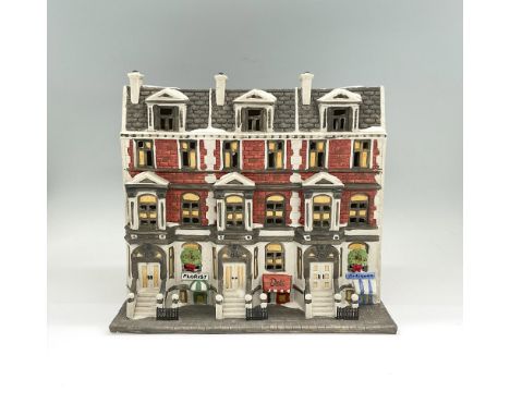 Handpainted matte porcelain figure of a four-story brownstone building with a florist, deli and antique shop on the ground fl