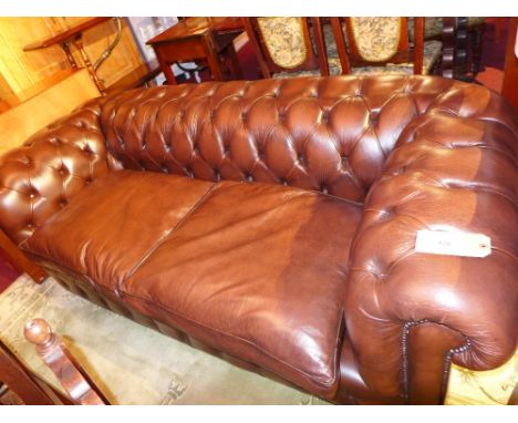 A Chesterfield sofa upholstered in buttoned brown leather with studded detail on turned mahogany feet