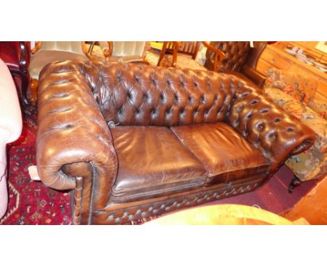 A Chesterfield two seater sofa upholstered in buttoned brown leather with studded detail 
