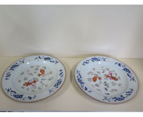 A pair of Chinese Qianlong period porcelain dishes, decorated with swimming carp beneath a blue peony border, diameter 35cm -