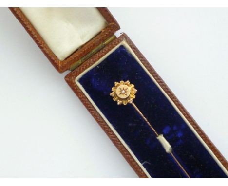 A late Victorian 9ct gold and split seed pearl stick pin, gypsy set within a pelleted and cannetille decorated starburst fram