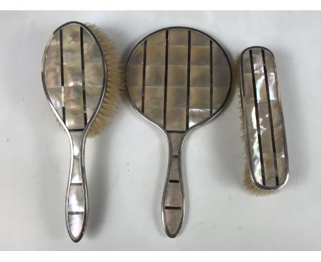 A George V silver and mother-of-pearl Modernist dressing table set, comprising hand mirror, hair brush and clothes brush, inl