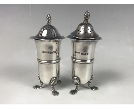 A pair of Edwardian silver pepperettes, each of elongated ovoid form with wavy everted rims, and three paw feet, M G Collingw