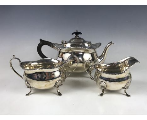 An early George V silver three-piece tea service, of Georgian influence, comprising tea pot, milk jug and sugar bowl, each it