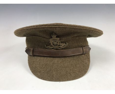 A British Army serge peaked cap, of other ranks' quality, bearing Royal Artillery cap badge, manufactured by Dunn &amp; Co