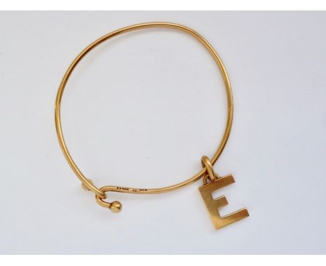 A vintage 9ct gold bangle with 9ct gold Gucci charm in the form of the letter 'E', 10.2g