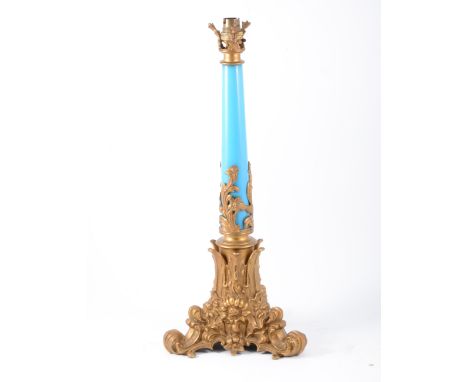 A gilded bronze and blue glass lamp base, triform scrolling base with acanthus leaves and flowers extending over plain blue r