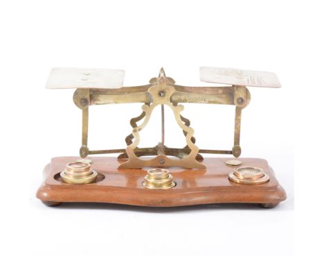A set of brass letter scales with brass weights giving the "Postal Rates" on one side, mounted on a mahogany base.