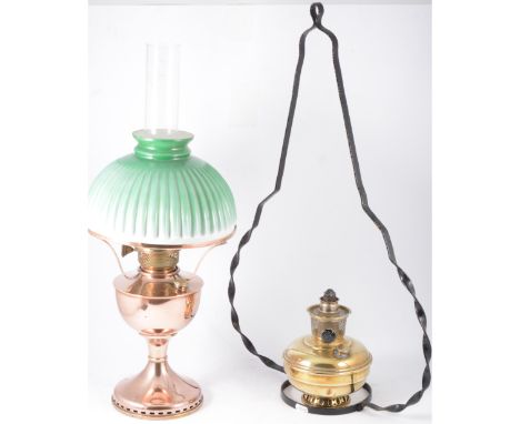 A brass hanging oil lamp with black iron frame, glass chimney and milk glass shade, a copper oil lamp with chimney and green 