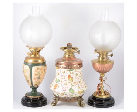 Three oil lamps, a large ceramic lamp decorated with apple blossom with copper and brass mounts on three brass scroll feet, 3