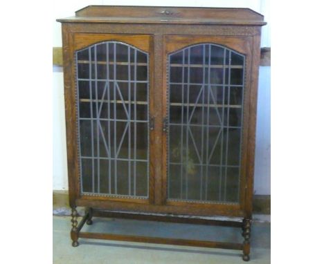 1930s oak display cabinet, with raised back and a pair of arch glazed doors on barley twist supports joined by stretchers (11