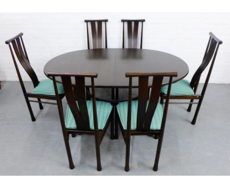 A dark elm Ercol dining suite comprising an extending table and set of six curved splat back dining chairs with green upholst