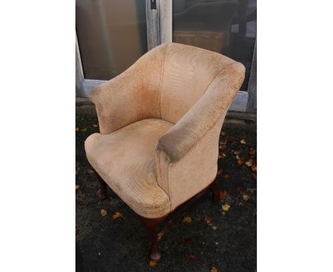 An early 20th century tub chair, upholstered in a light tan weave, on cabriole stretchered supports