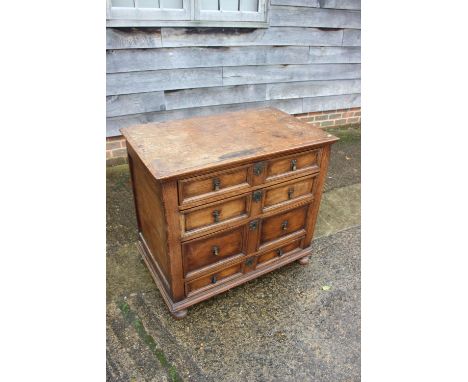A late 17th century oak chest of four long drawers with fielded panel fronts and axe head drop handles, on bun feet, 36" wide