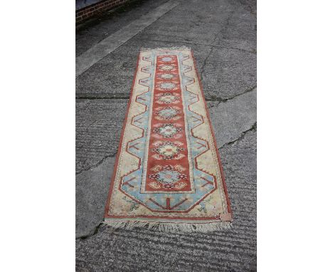 A Turkish Milas runner with nine medallions and geometric designs on a rust ground in shades of pink, light blue and natural,