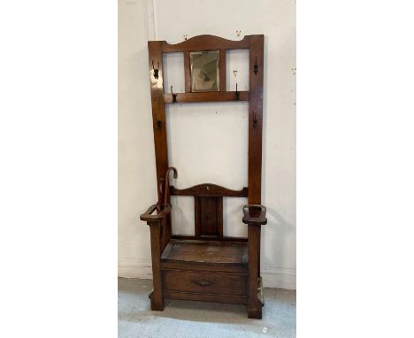 An oak hall stand with six coat hangers, mirror to centre and seat storage under (H185cm W77cm D39cm)