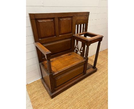 An oak hall stand with panelled seat opening to storage and flanked by a stick stand (H115cm W110cm D45cm)