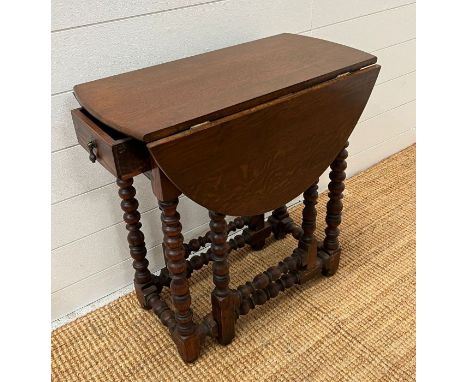 An oak gate leg table with drawer to centre 