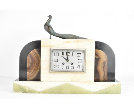 An Art Deco marble and onyx 8 day mantle clock, surmounted by a metal peacock, rectangular silvered dial with Arabic numerals
