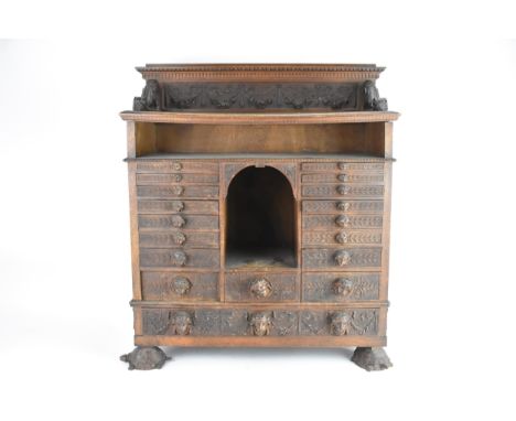 An early 20th century continental table top cabinet, having a raised back with carved floral swags supported by two acanthus 