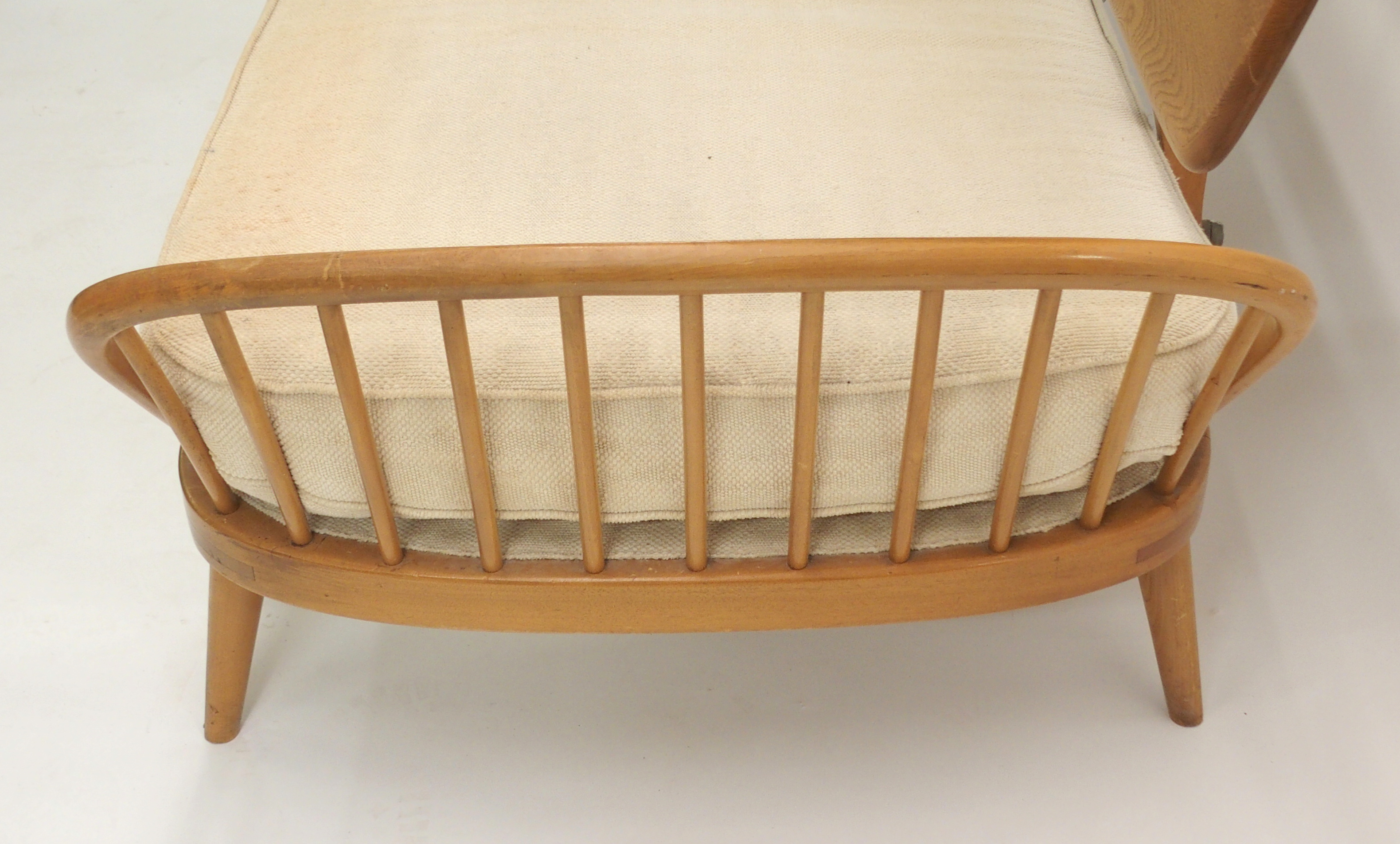 An Ercol day bed with shaped plank back, arched spindle sides with