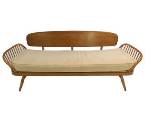 An Ercol day bed with shaped plank back, arched spindle sides with cream cushions, 208cm wide This item is offered for sale a