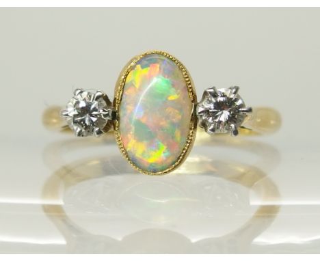 An 18ct gold and platinum opal and diamond ring the opal is approx 8.2mm x 5.1mm x 2.1mm and flanked by two diamonds of estim