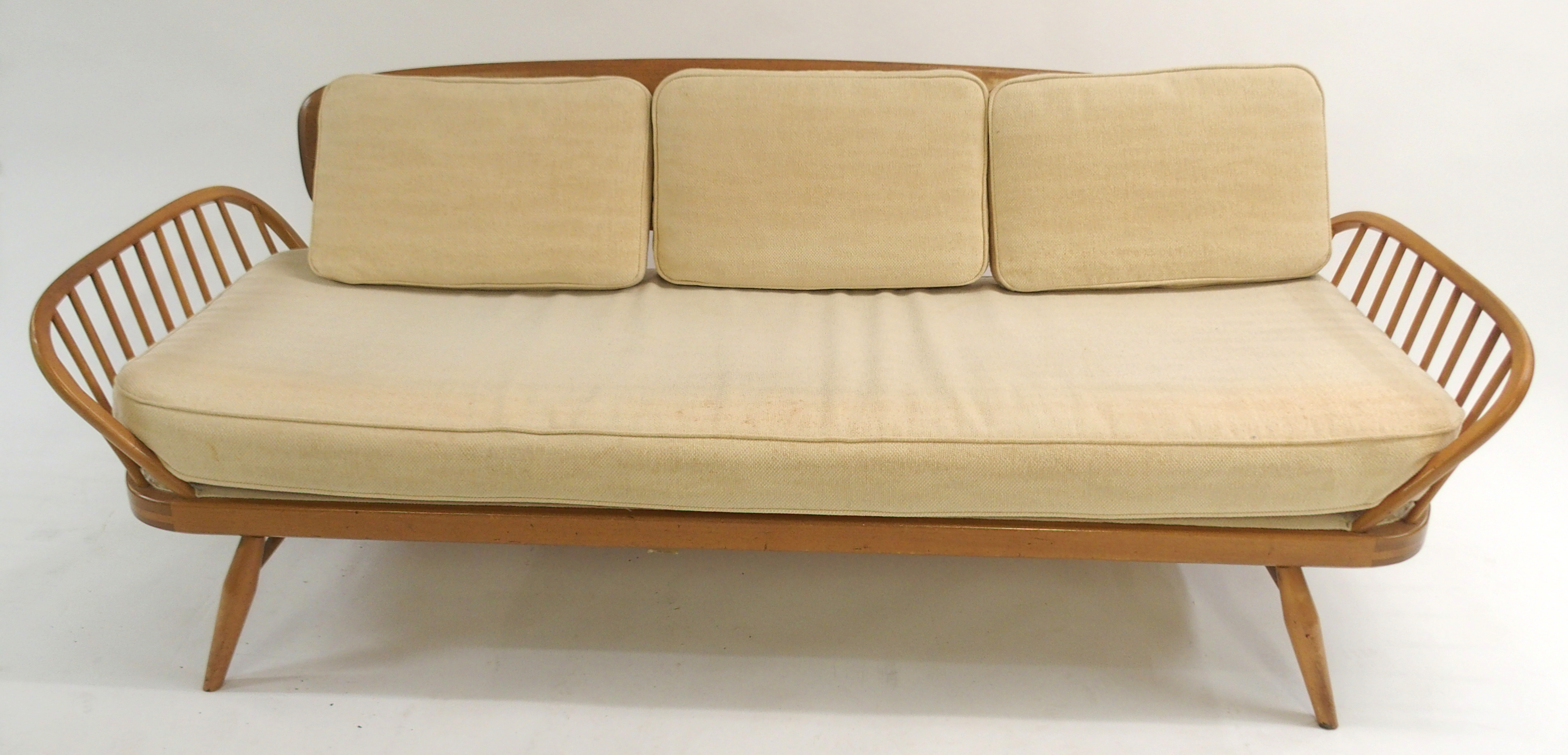 An Ercol day bed with shaped plank back, arched spindle sides with