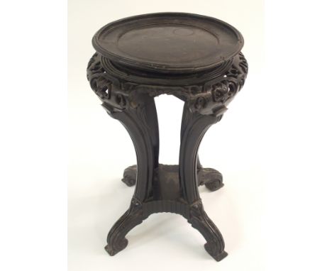 A Chinese hardwood pedestal with carved and pierced shoulder above fluted scroll legs joined by a block stretcher on scroll f