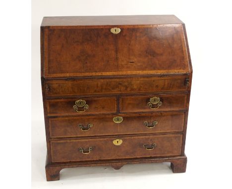 A Georgian walnut and line inlaid bureau the fall flap enclosing pigeon holes, drawers and sliding drawer above four graduate