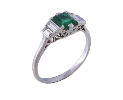  An Art Deco emerald and diamond ring,   the step cut emerald with canted corners, to stepped baguette cut diamond shoulders,