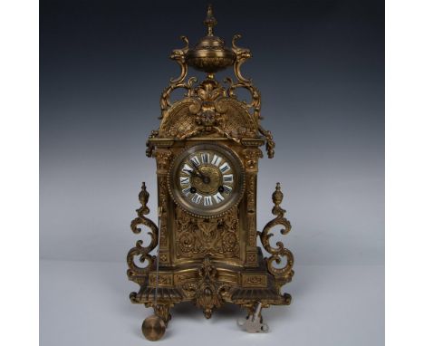 This antique mantle clock, meticulously crafted from brass, boasts a square silhouette. Adorned with intricate Arabesque patt