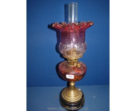 An Oil Lamp with a pink to pale pink ombre shade with fluted rim, pink to orange ombre reservoir on a brass and ceramic base,