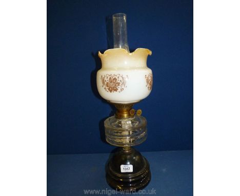 An Oil Lamp with fluted shade in yellow to white ombre decorated with painted flowers, with clear reservoir, standing on wood
